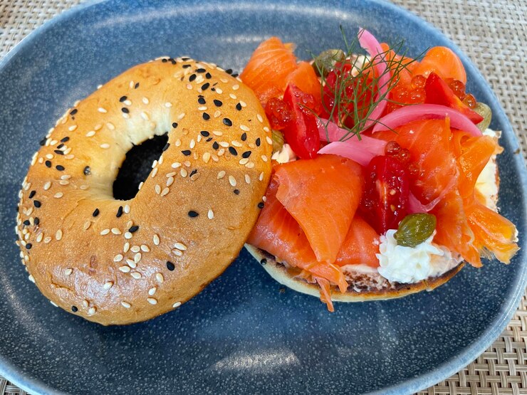Golden homemade protein bagels on a rustic wooden counter with oats and flour dusting